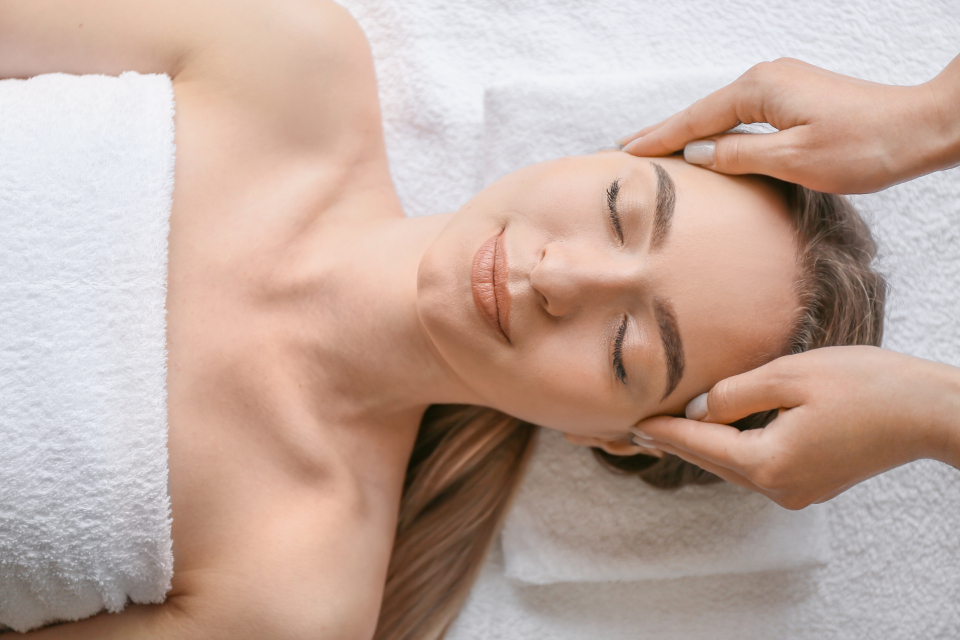 Therapeut behandelt Nacken und Kopf einer Klientin auf der Massageliege