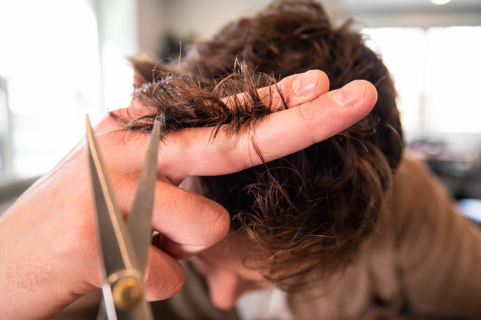 Nahaufnahme: eine Schere schneidet eine Haarsträhne